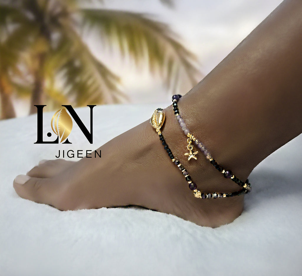 Cheville avec bracelet de cheville Island Essence perles noires et améthyste, coquillage cauri et étoile de mer en or, logo de la marque sur le pied 