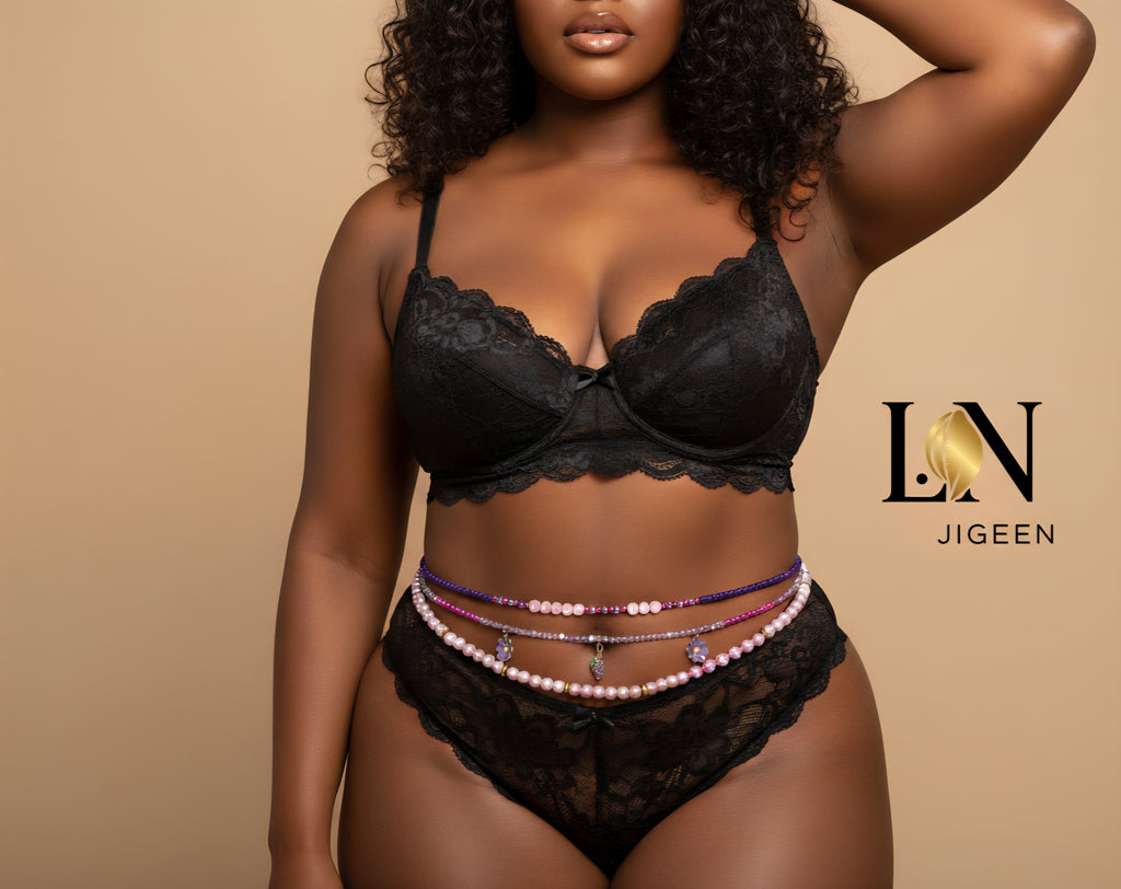 Gros plan sur une femme noire aux formes généreuses, vêtue d'une lingerie en dentelle noire. Elle porte trois rangs de perles de taille (bijoux de corps) aux couleurs mauve et rose. Logo de la marque "LN JIGEEN" centré au-dessus des perles.