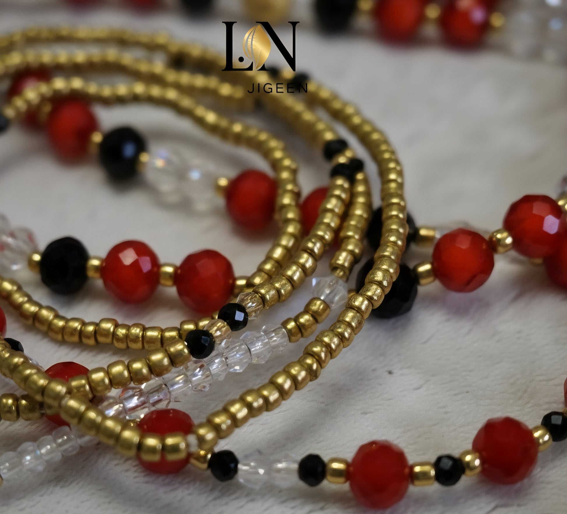 Gros plan détaillé des perles de hanche LN JIGEEN. Mise au point sur le travail minutieux des perles rouges taillées en cristal et des perles de rocaille noires et transparentes. Montre la finesse de l'assemblage et la haute qualité des matériaux. Idéal pour mettre en valeur l'artisanat du bijou.